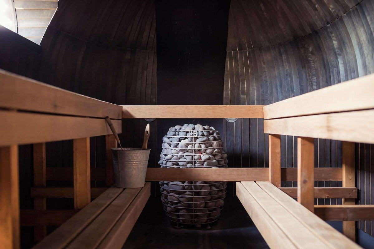 Modern sauna heater with a stone basket installed in a wood-lined sauna room